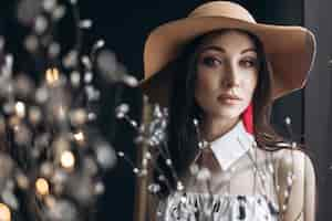 Free photo adorable woman in beige hat and with fashion look poses in the dark studio