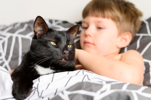 Free photo adorable young boy petting his cat