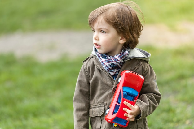 Adorable young boy with toy car looking away