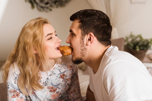 Adorable young couple sharing a croissant