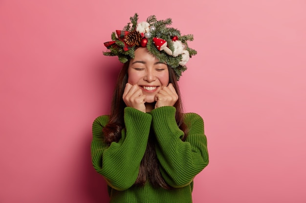 Free photo adorable young lady smiles pleasantly wearing festive wreath on head