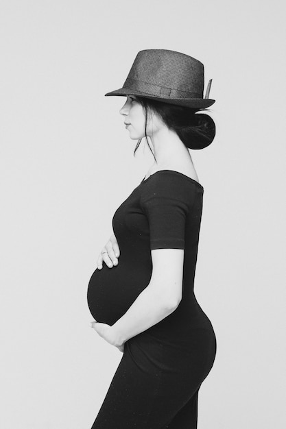 Free Photo adorable young mum in black dress posing for the camera with her tummy, black and white picture isolated on white background