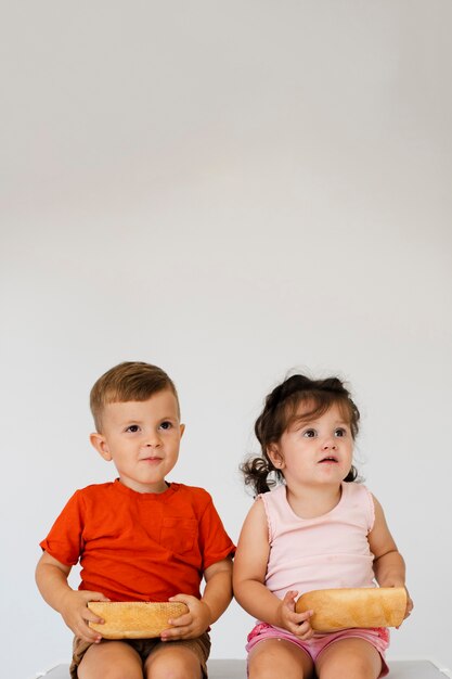 Adorable young siblings holding bread