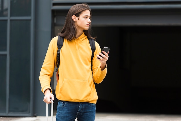 Adorable young traveler holding his phone