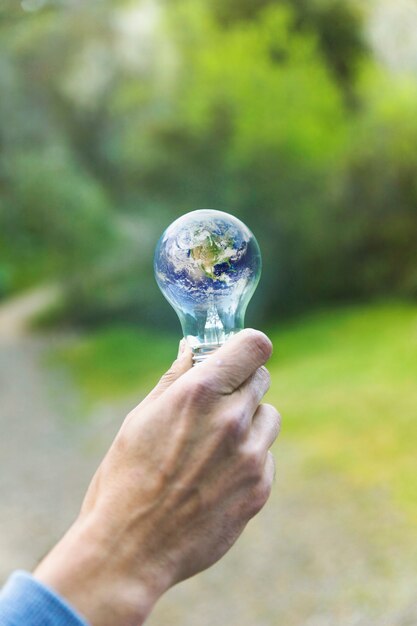 Adult arm keeping lamp with planet