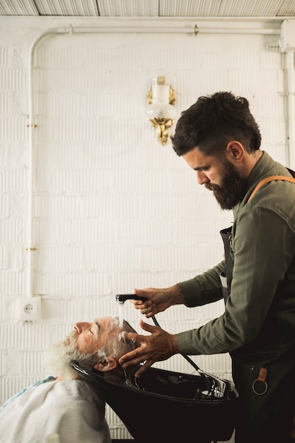 Free Photo adult barber washing old man hair on backwash