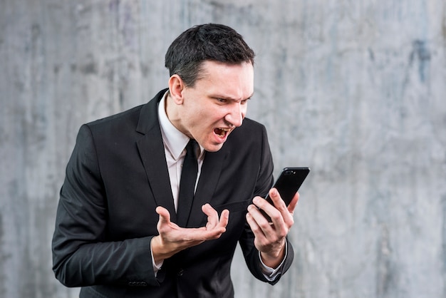 Adult businessman getting angry and yelling at phone 