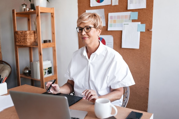 Adult designer works with laptop in her office