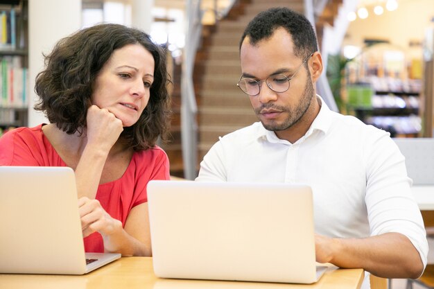 Adult female student looking at monitor of college mate