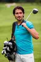 Free photo adult man carrying golf clubs outdoors