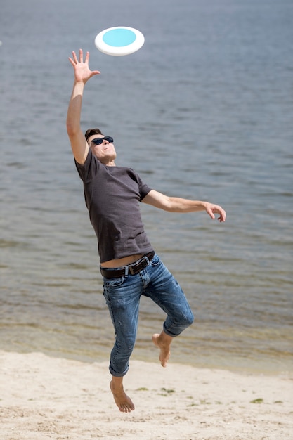 Free photo adult man catching frisbee on beach