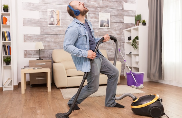 Free photo adult man listening rock music on headphones while cleaning the house