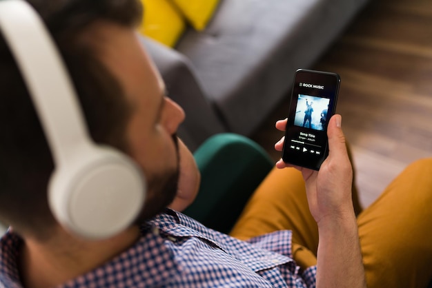 Free photo adult man playing a song on his smartphone and listening to music with wireless headphones