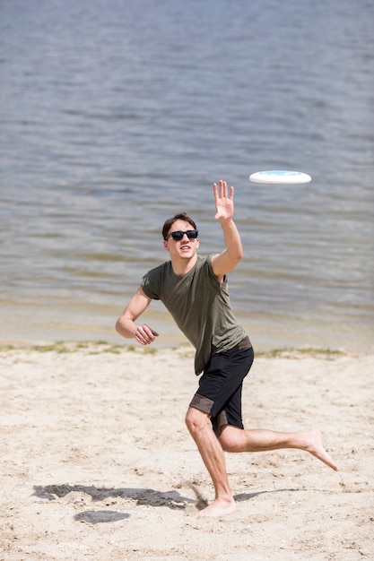 Adult man running on shore and catching frisbee 