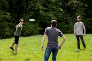 Free photo adult men resting in park by playing frisbee