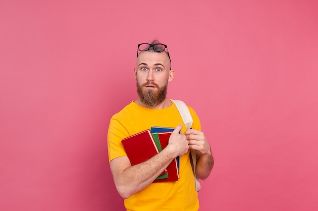 Free Photo adult student cheerful casual wear guy with beard and backpack holding books isolated on pink