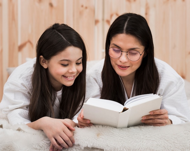 Adult woman reading a book with young girl