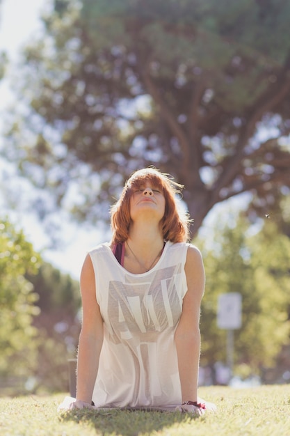 Adult woman in upward-facing dog pose in park