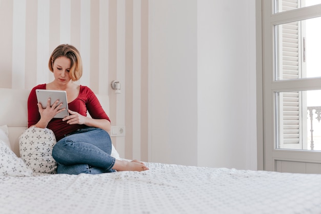 Adult woman with tablet on bed