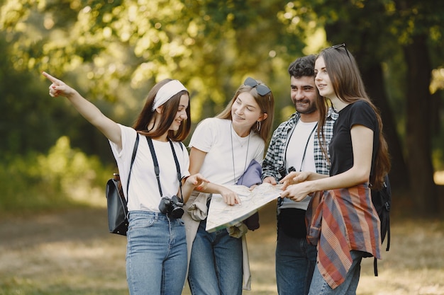 Adventure, travel, tourism, hike and people concept. Group of smiling friends in a forest. Man with binocularus.