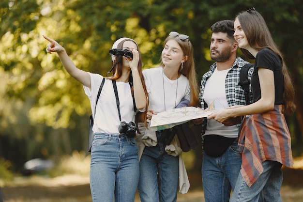 Adventure, travel, tourism, hike and people concept. Group of smiling friends in a forest. Man with binocularus.