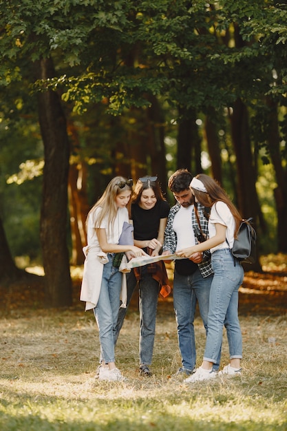 Adventure, travel, tourism, hike and people concept. Group of smiling friends in a forest. Man with binocularus.