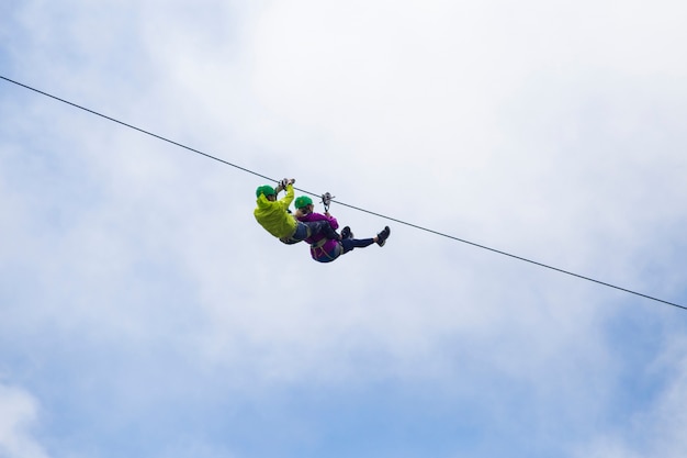 Free photo adventurous tourist zip lining against cloudy sky