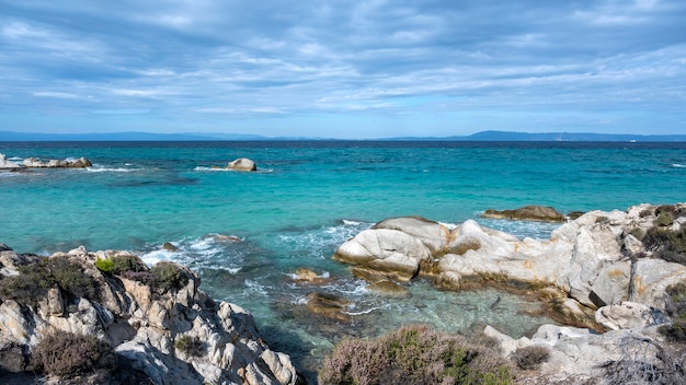 Free Photo aegean sea coast with greenery around, rocks and bushes, blue water with waves, greece