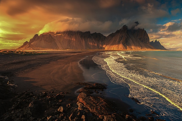 Free photo aerial beautiful shot of a seashore with hills on the background at sunset