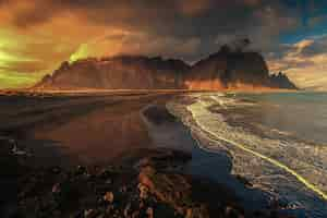 Free photo aerial beautiful shot of a seashore with hills on the background at sunset