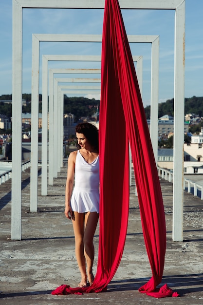 Free photo aerial dance on rooftop, sexy brunette silk dancer in white dress