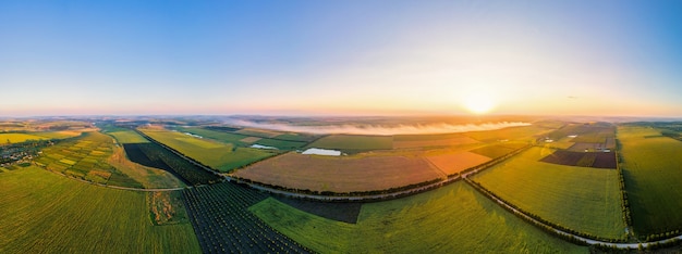 Aerial drone panorama view of nature in Moldova at sunset. Smoke from a fire, wide fields, road, sun