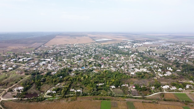 Aerial drone view of village in Moldova, multiple buildings and trees, fog in the air