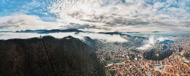 Free photo aerial drone wide view of brasov in winter romania residential buildings mountains low clouds