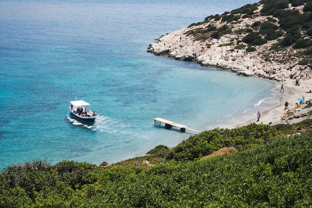 Free photo aerial photography shot of a boat approaching the small beach in amorgos, greece