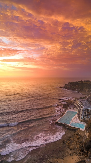 Free photo aerial shot of a beach with a large swimming pool of a hotel and the sea during sunset