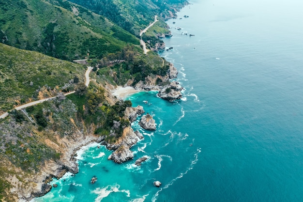 Aerial shot of the beautiful shoreline of the sea with rocks and greenery on the beach