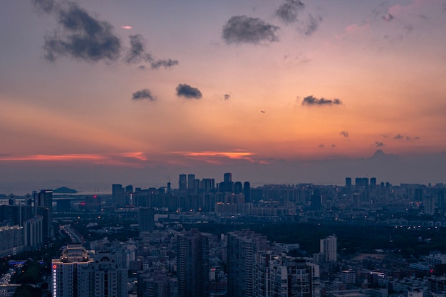 Aerial shot of a big city under an orange-blue cloudy sky at sunset