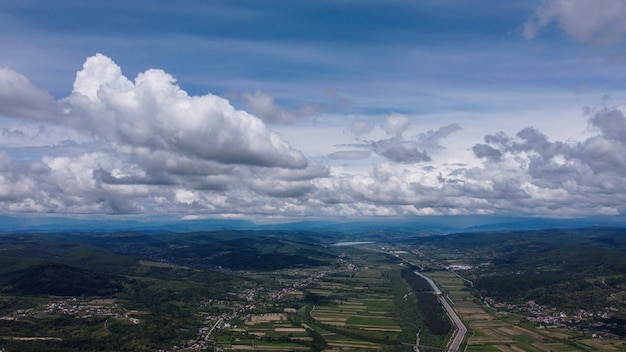 Free photo aerial shot of buildings with fields and mountains under the cloudy sky