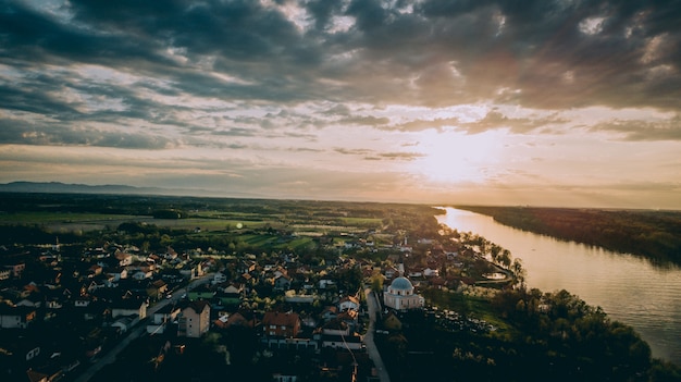 Free photo aerial shot of a city near a river and grassy fields under a cloudy sky