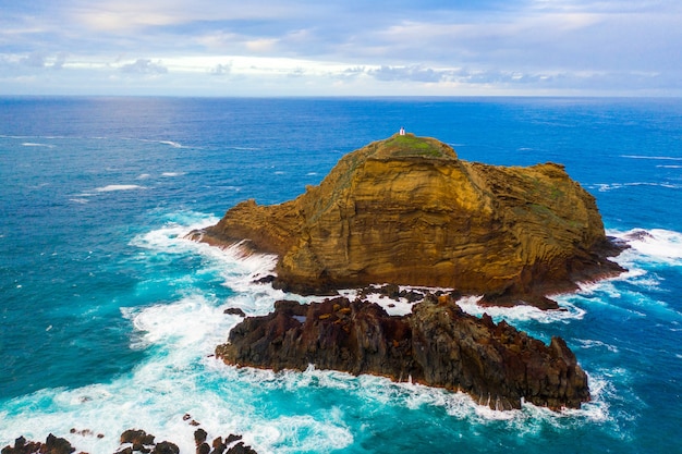 Free photo aerial shot of a cliff near the sea with waves splashing