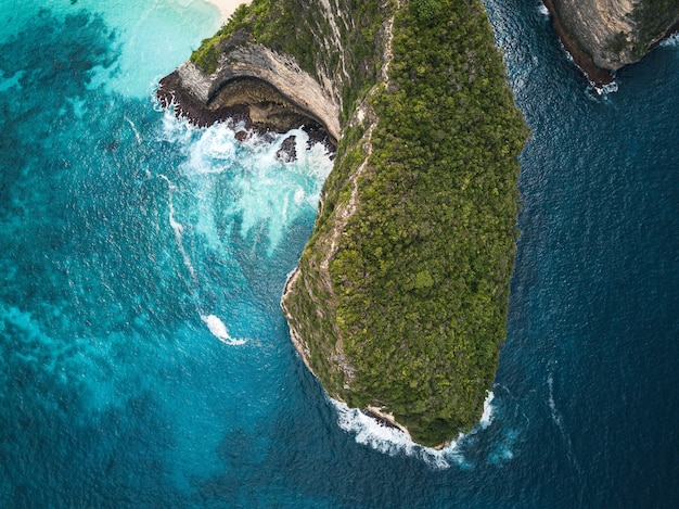 Aerial shot of the cliffs covered in greenery surrounded by the sea