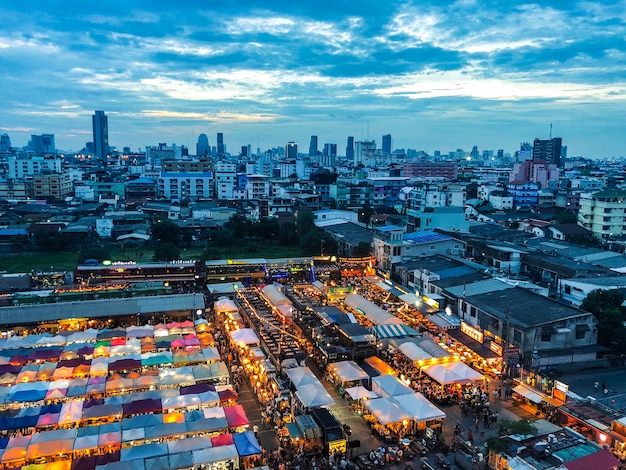 Aerial shot of market tents near buildings under a blue sky