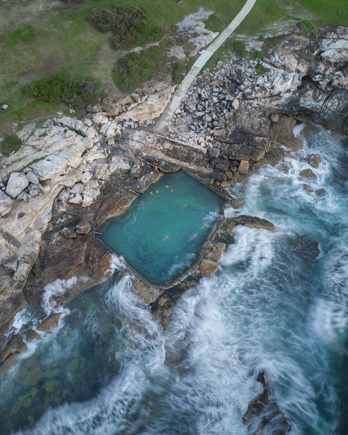 Free Photo aerial shot of people swimming in a large pool built on the rocky coast in thailand