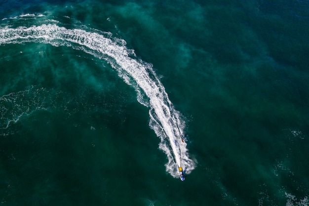 Aerial shot of a person jet skiing in bright green seawater