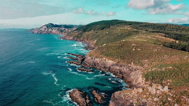 Aerial shot of rocky cliffs near a turquoise seascape