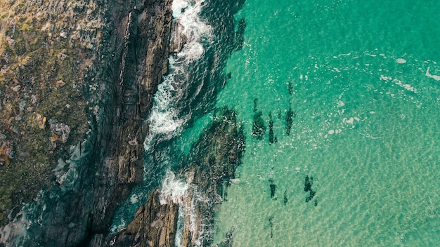 Aerial shot of rocky cliffs near a turquoise seascape