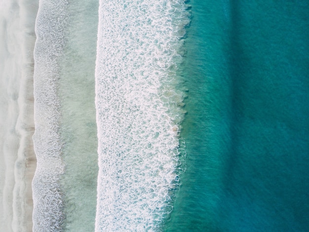 Free photo aerial shot of sea waves hitting the shore at daytime