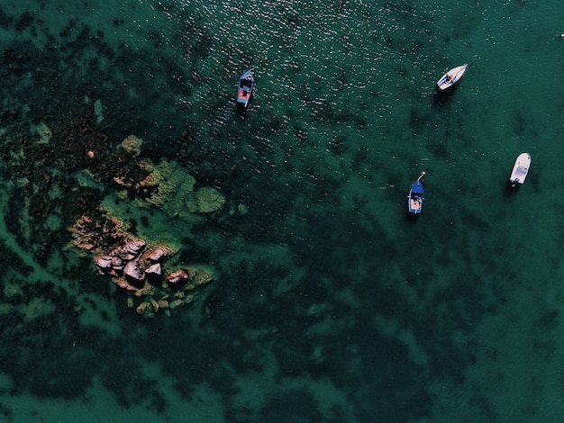 Free photo aerial shot of a sea with boats near a rock at daytime