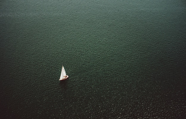 Free Photo aerial shot of a small boat sailing in the wide beautiful ocean